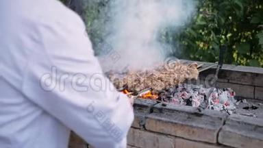 厨师在煤块上烤猪肉，在烤架上烤猪肉，从砖块上烤猪肉，有烟